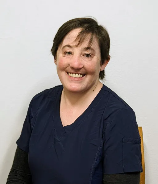 A woman sitting in front of a white wall.