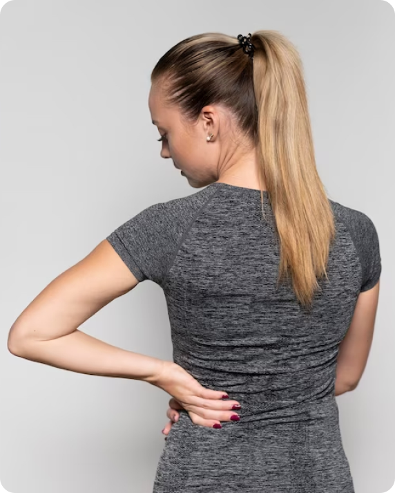 A woman with her hands on the back of her lower back.