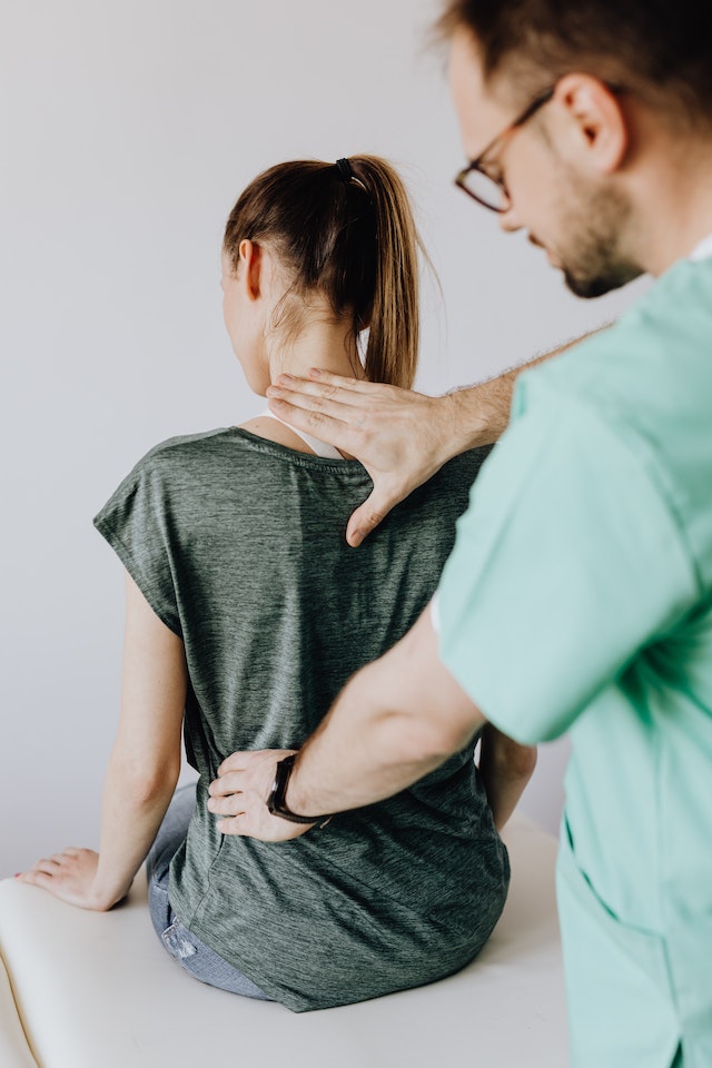 A person with their back turned and another person touching her back.