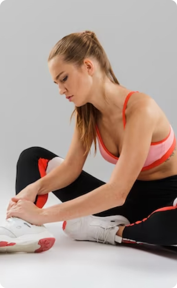 A woman in pink top and black pants sitting on the ground.