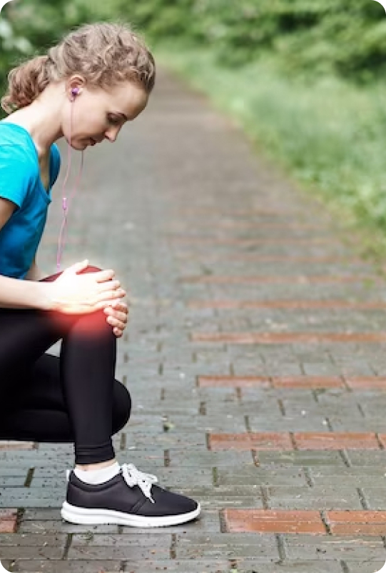 A woman sitting on the ground with her hands in her knees.